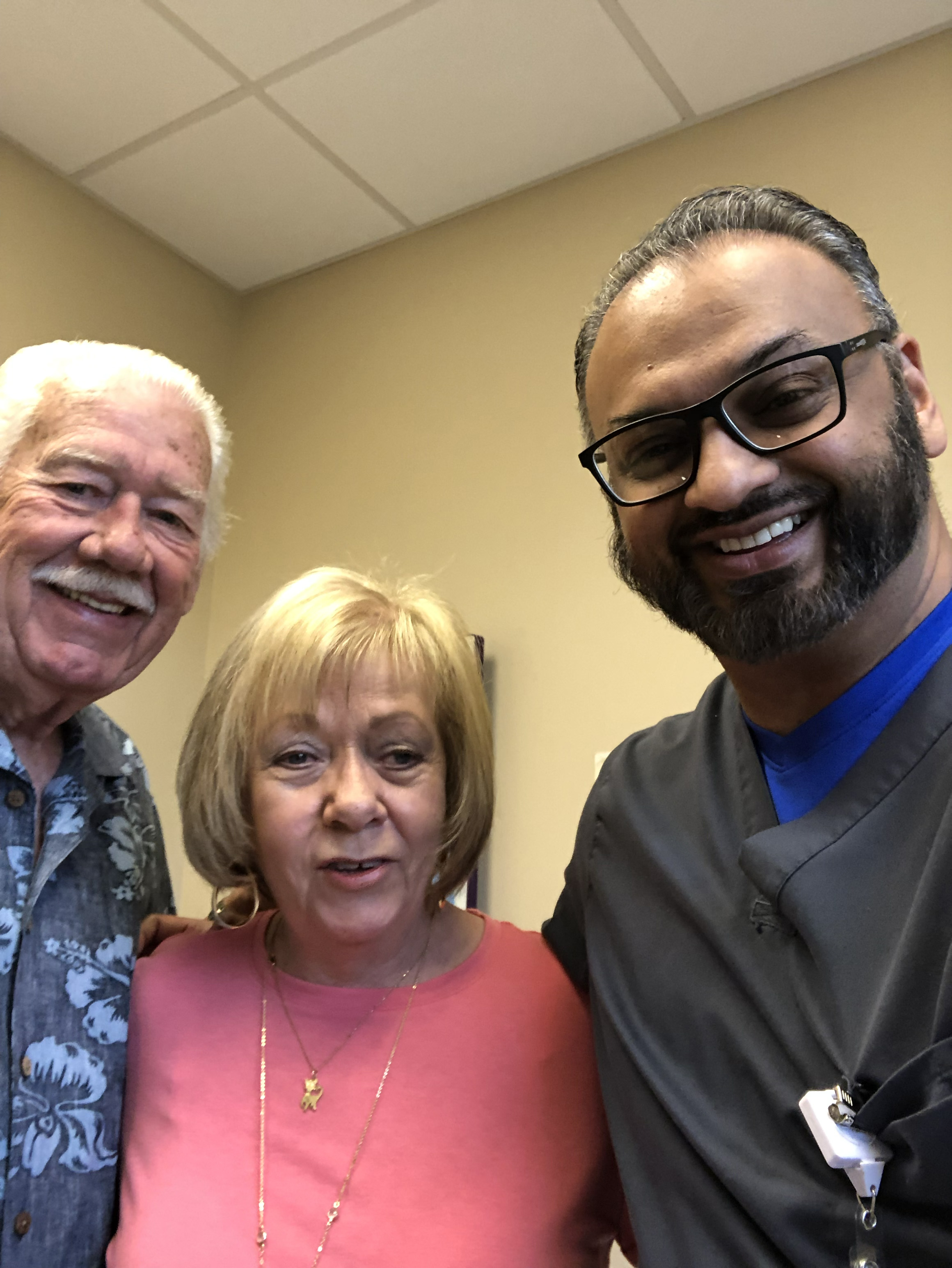 Dr. Syed Hasan smiling with patients in a clinical setting